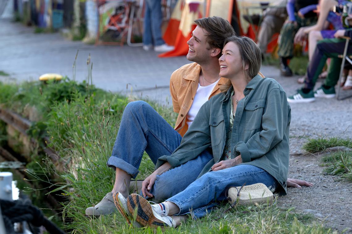 a white man and women sit on a patch of grass smiling