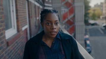 A black woman stands on a London housing estate balcony