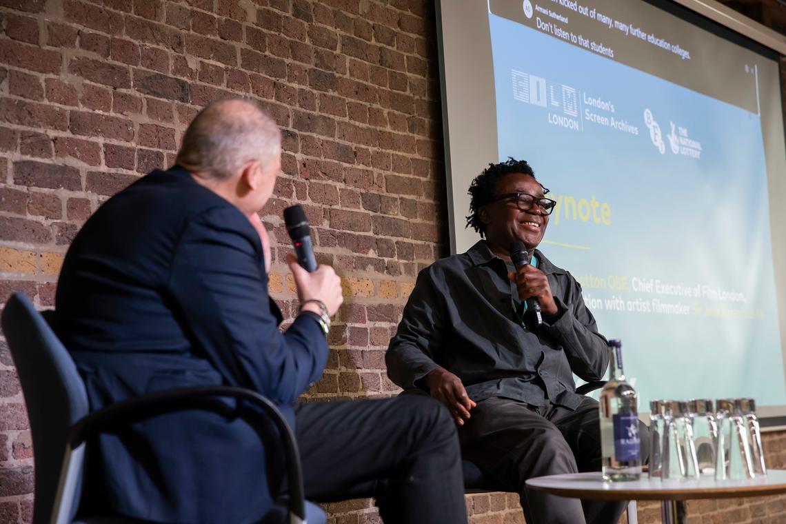 Adrian and John sat at table on the stage
