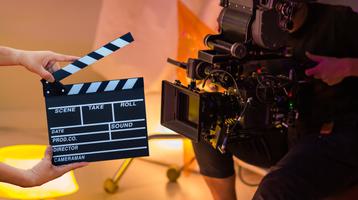 Person operating a camera behind a clapperboard on set