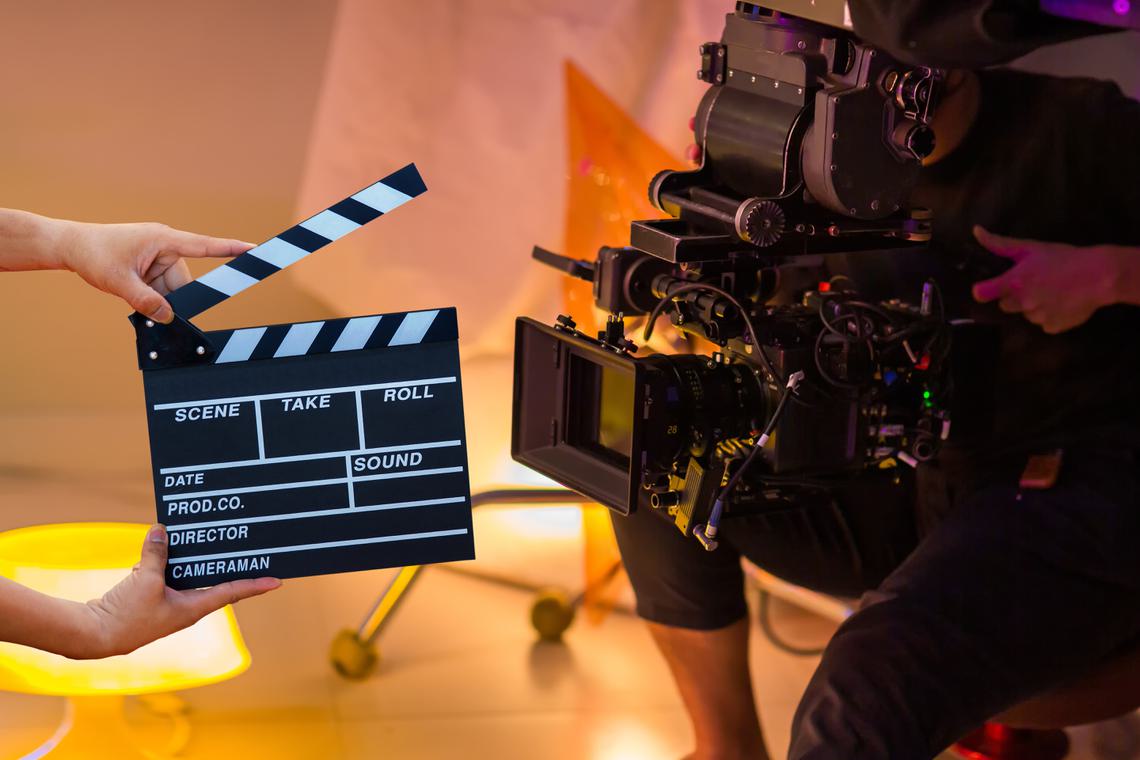 Person operating a camera behind a clapperboard on set