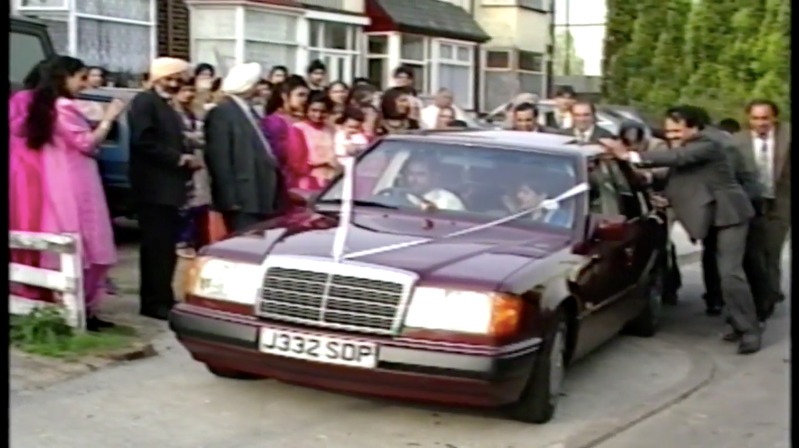 A couple drives away from a wedding in archive footage.